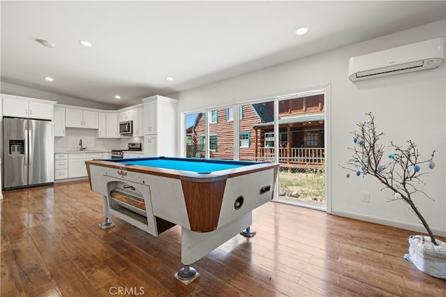 game room featuring plenty of natural light, hardwood / wood-style floors, and a wall mounted air conditioner