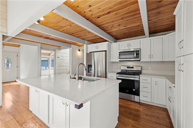 kitchen with beam ceiling, sink, a center island with sink, white cabinetry, and stainless steel appliances