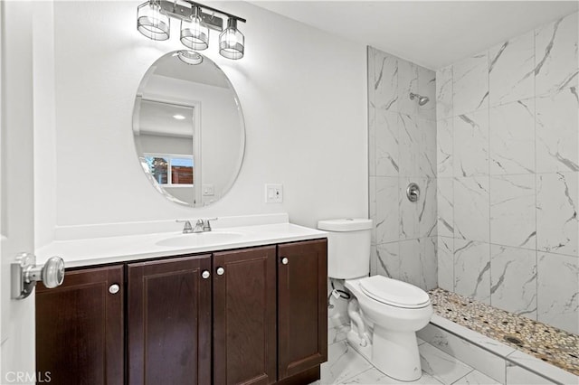 bathroom featuring vanity, toilet, tiled shower, and marble finish floor