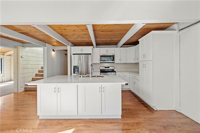kitchen featuring beam ceiling, a sink, light countertops, stainless steel appliances, and wood ceiling