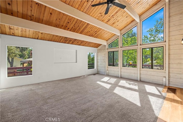 unfurnished living room featuring wooden walls, wooden ceiling, ceiling fan, beamed ceiling, and carpet floors