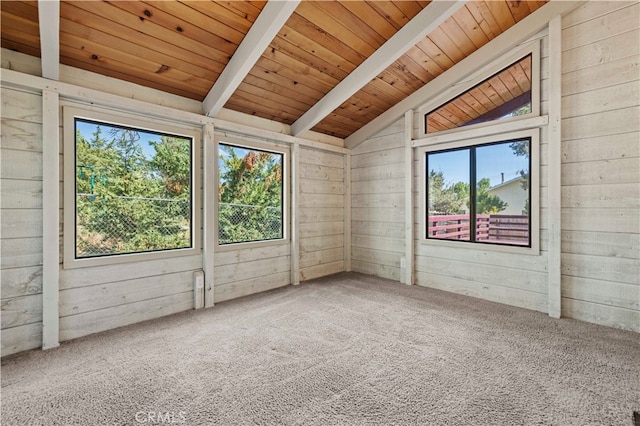 empty room with wooden ceiling, a healthy amount of sunlight, lofted ceiling with beams, and wood walls