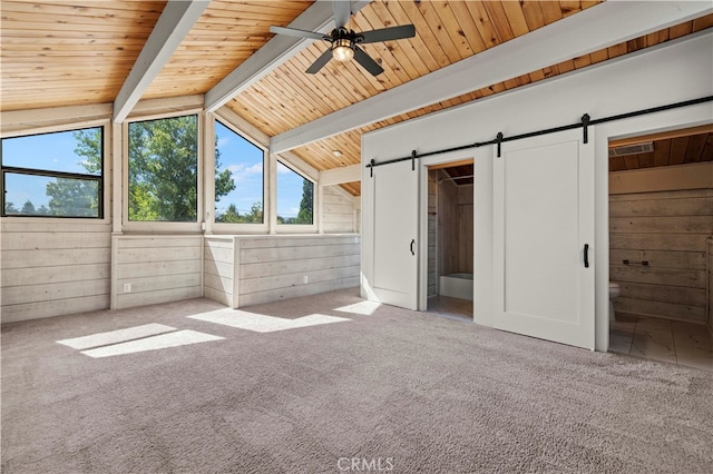 unfurnished bedroom with vaulted ceiling with beams, connected bathroom, wooden walls, and ceiling fan