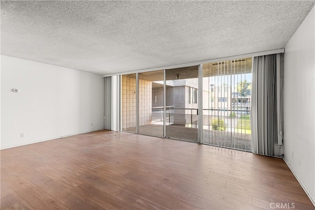 empty room featuring hardwood / wood-style floors, expansive windows, and a textured ceiling