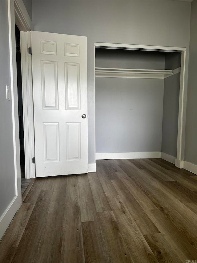 unfurnished bedroom with a closet and dark hardwood / wood-style flooring