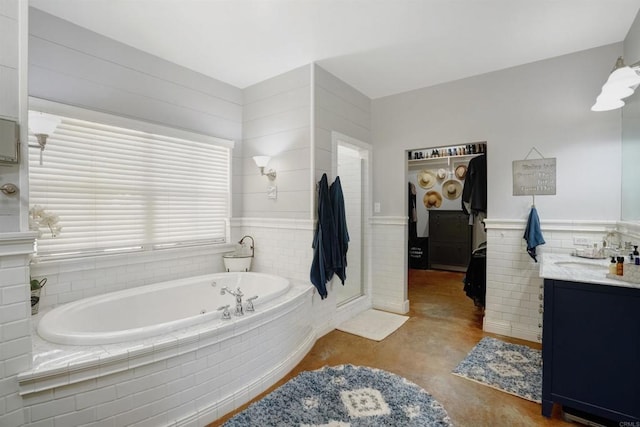 bathroom featuring vanity, concrete floors, and tiled tub