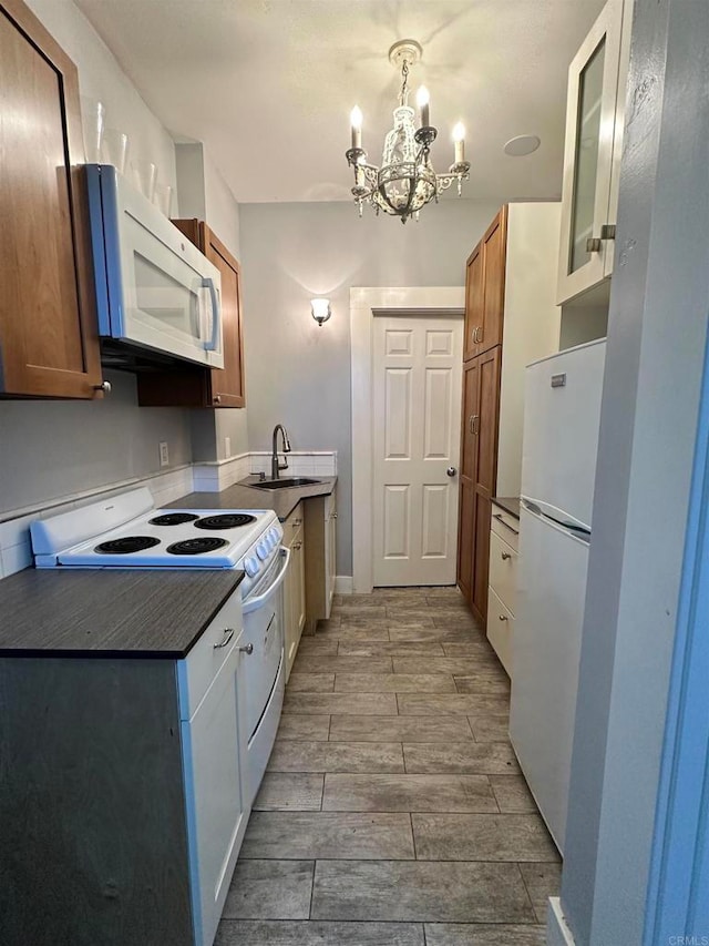 kitchen with decorative light fixtures, a chandelier, sink, and white appliances