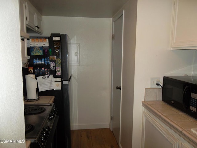 kitchen with white cabinets, wood-type flooring, tile counters, and black appliances