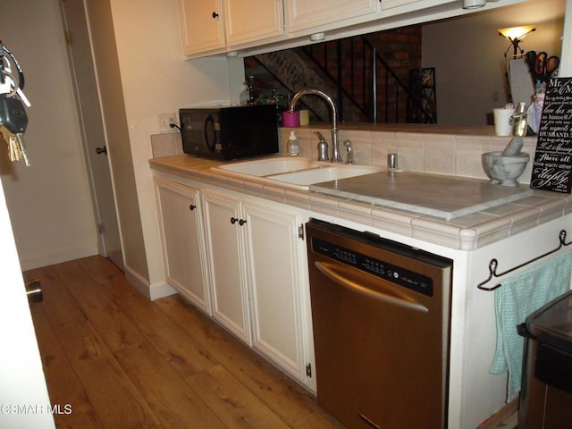 kitchen featuring stainless steel dishwasher, tile counters, light hardwood / wood-style floors, and sink