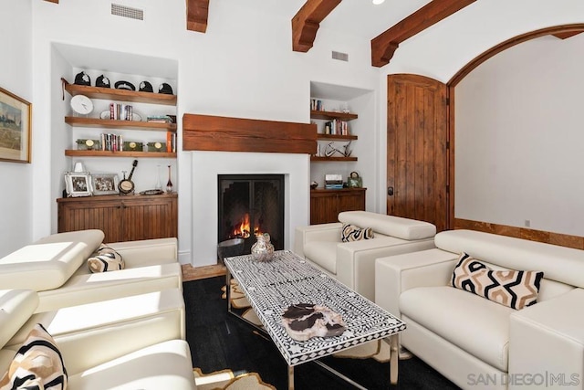 living room with beamed ceiling and built in features