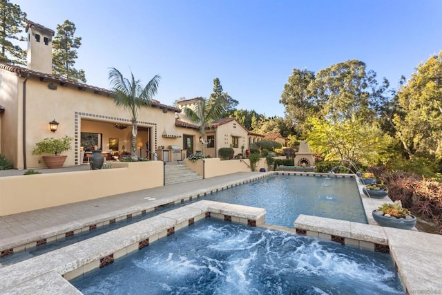 view of pool with an in ground hot tub, pool water feature, a fireplace, and a patio area