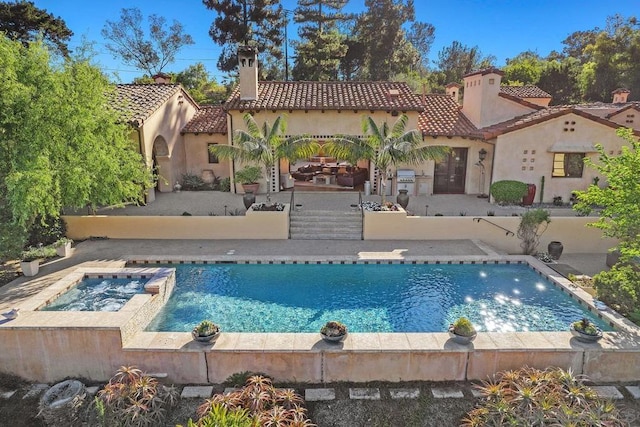 rear view of property featuring a pool with hot tub and a patio area