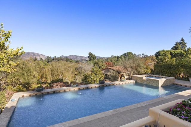 view of swimming pool with a mountain view and an in ground hot tub