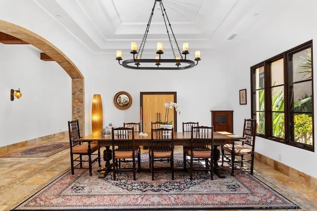 dining area with a tray ceiling, a chandelier, and a high ceiling