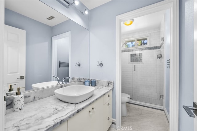 bathroom with vanity, toilet, and a shower with door