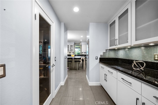 kitchen with white cabinets, dark stone countertops, and tasteful backsplash