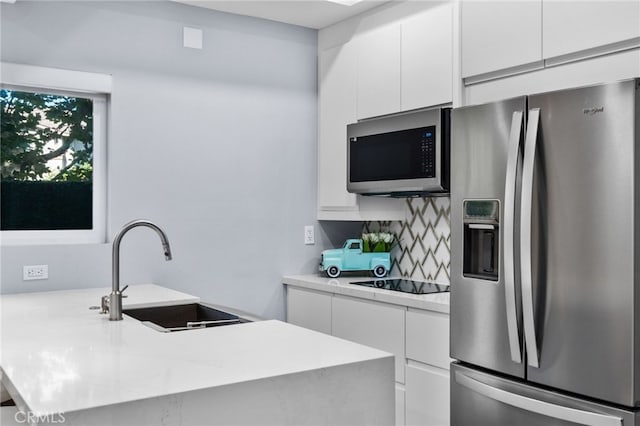 kitchen featuring white cabinets, sink, kitchen peninsula, stainless steel appliances, and decorative backsplash