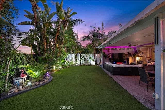 yard at dusk featuring a patio, an outdoor living space, and ceiling fan