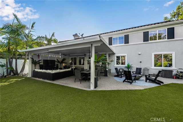 back of property with a patio, a yard, an outdoor living space, and ceiling fan