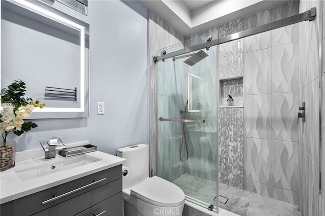 bathroom featuring vanity, toilet, and a shower with shower door