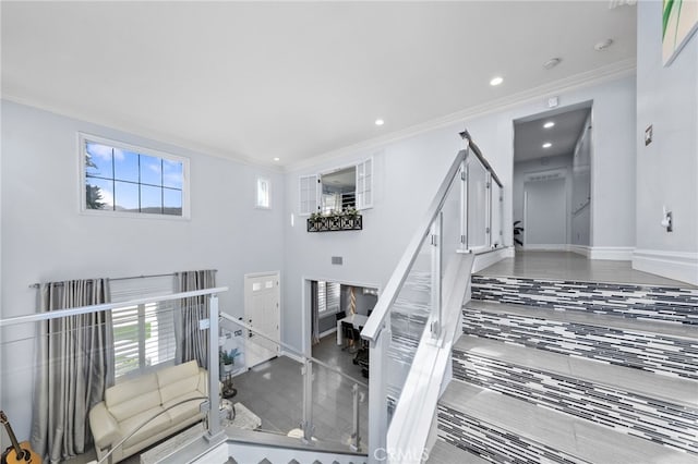 stairway with a fireplace, a healthy amount of sunlight, and crown molding