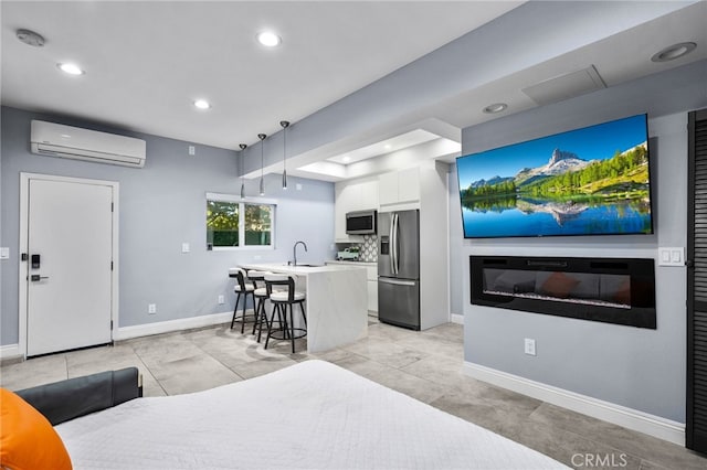 bedroom with a wall mounted AC, sink, and stainless steel fridge with ice dispenser