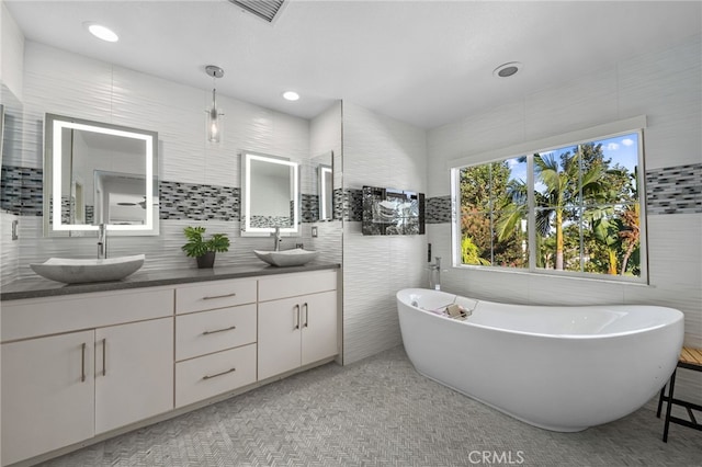 bathroom with vanity, tile walls, and a bath