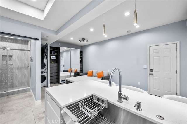 kitchen featuring stacked washer / drying machine, sink, pendant lighting, and a skylight