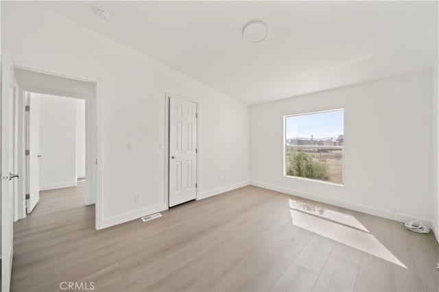 empty room with vaulted ceiling and light wood-type flooring