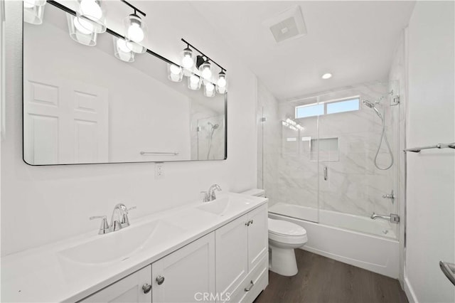 full bathroom featuring hardwood / wood-style floors, vanity, toilet, and bath / shower combo with glass door