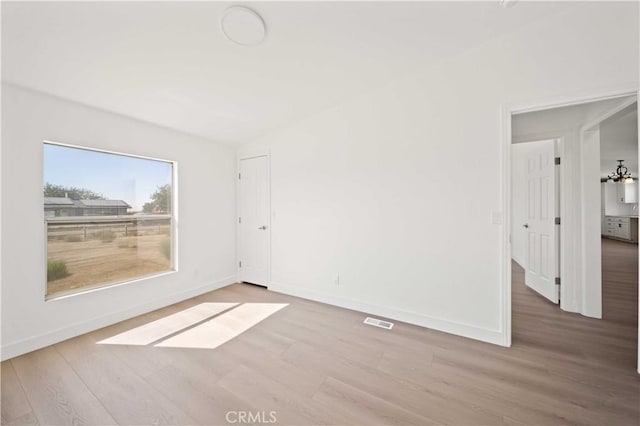 unfurnished room featuring a chandelier and hardwood / wood-style floors