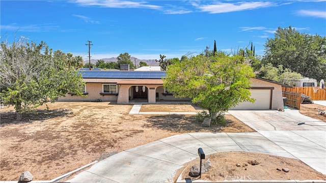 ranch-style home featuring solar panels and a garage