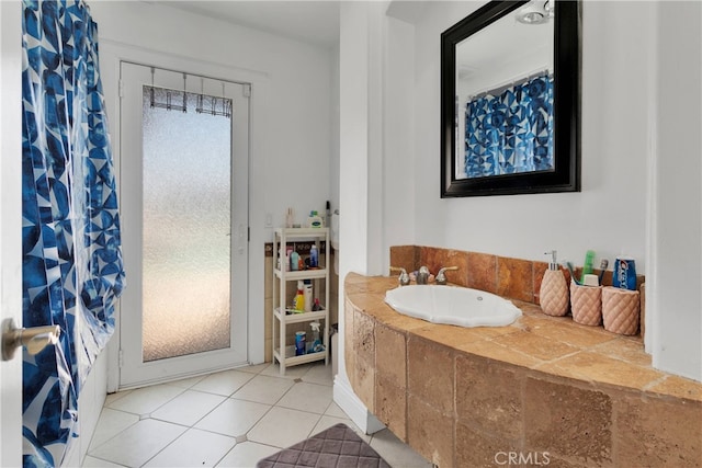 bathroom featuring tiled tub, sink, and tile patterned flooring