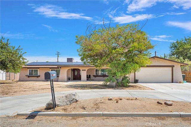 ranch-style home with a garage and solar panels