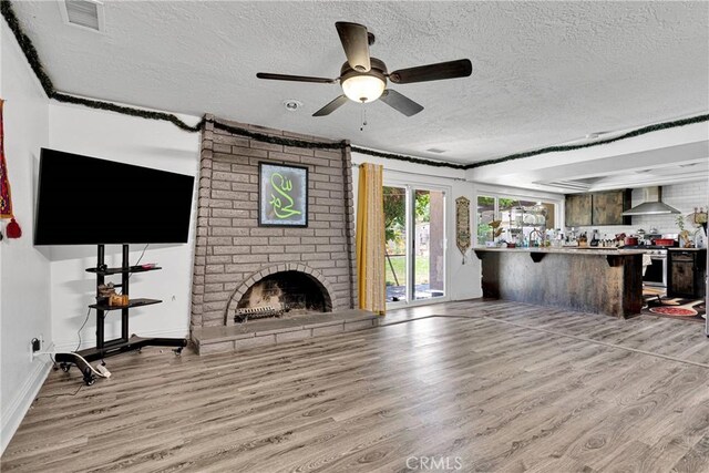 living room featuring light wood-type flooring, a textured ceiling, and ceiling fan