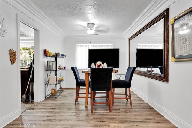 dining area with ceiling fan, hardwood / wood-style flooring, ornamental molding, and a textured ceiling