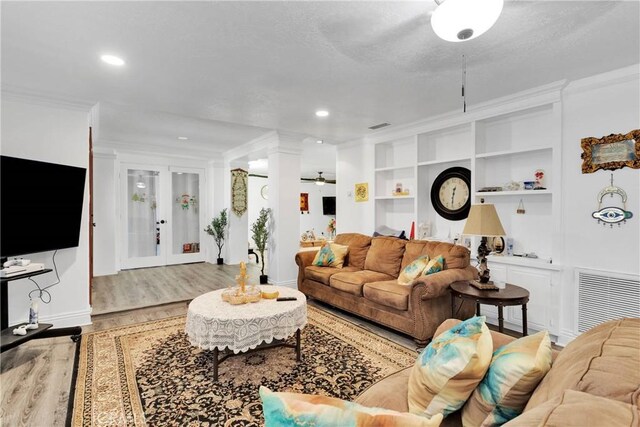 living room with light hardwood / wood-style floors, a textured ceiling, crown molding, french doors, and built in features