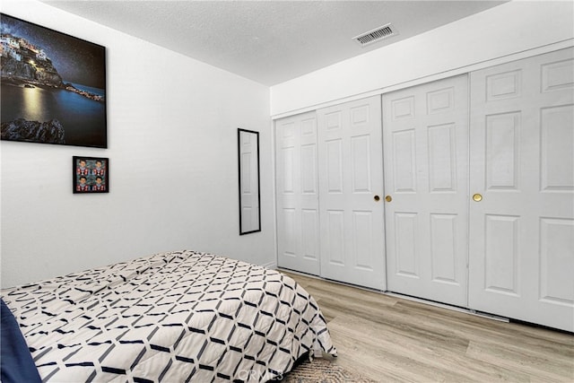 bedroom featuring light hardwood / wood-style floors, a closet, and a textured ceiling