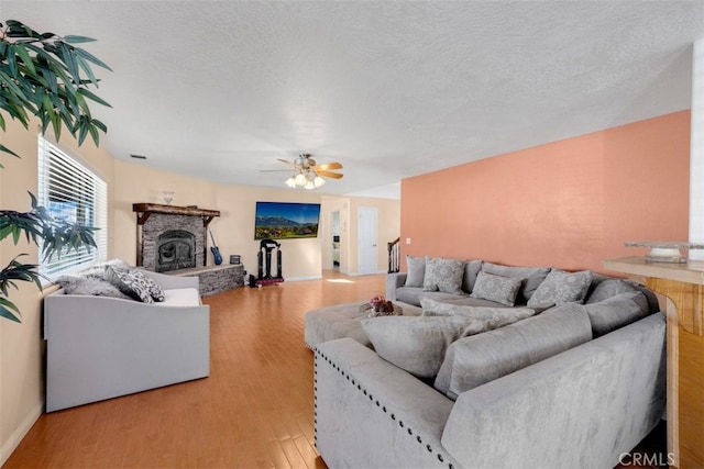 living room with hardwood / wood-style floors, ceiling fan, a fireplace, and a textured ceiling