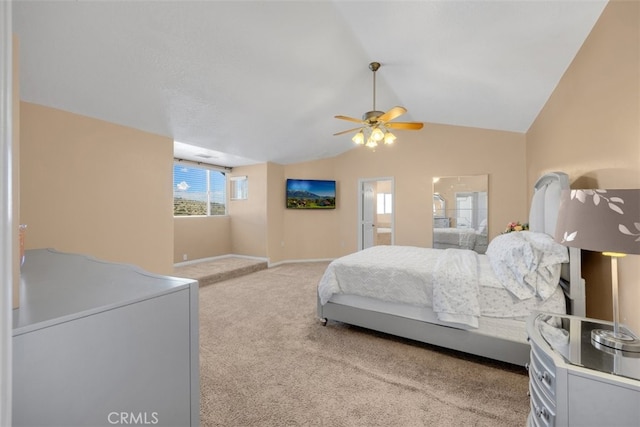 bedroom with ceiling fan, ensuite bathroom, light carpet, and lofted ceiling