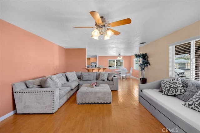 living room with a textured ceiling, light hardwood / wood-style floors, a wealth of natural light, and ceiling fan