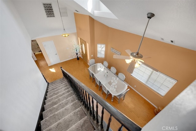 stairway featuring hardwood / wood-style flooring, ceiling fan, and high vaulted ceiling