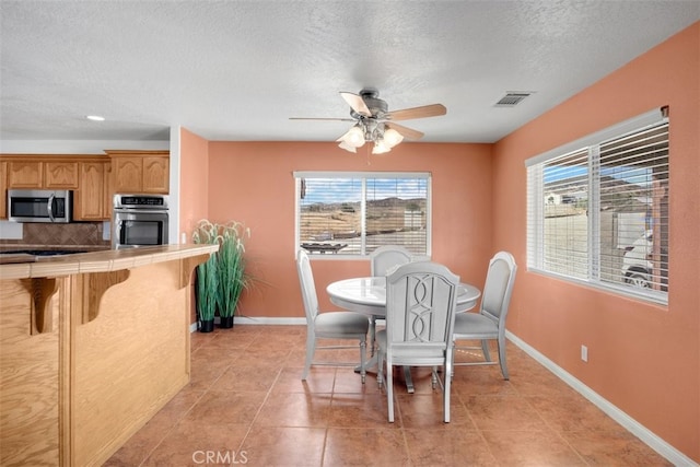 tiled dining space with ceiling fan and a textured ceiling