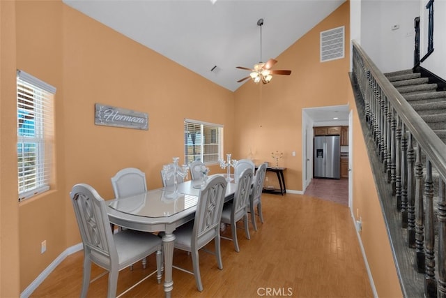 dining space with hardwood / wood-style floors, ceiling fan, and high vaulted ceiling