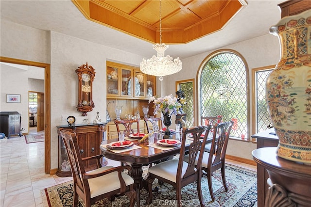 dining area with a notable chandelier, a raised ceiling, and coffered ceiling