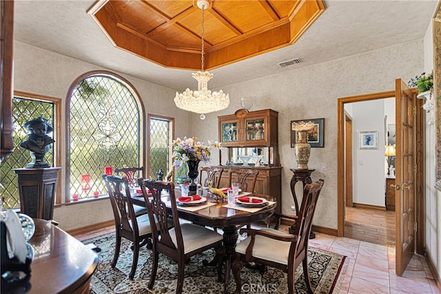 dining room with a notable chandelier, a raised ceiling, and wood ceiling