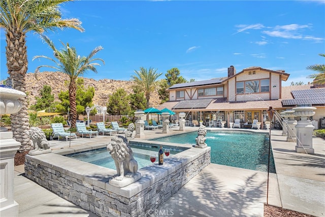 view of swimming pool featuring an in ground hot tub, a mountain view, pool water feature, and a patio area