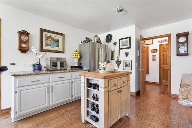 kitchen with white cabinets, hardwood / wood-style flooring, high quality fridge, and a center island