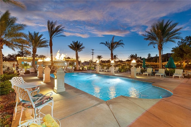 pool at dusk featuring a patio area and pool water feature