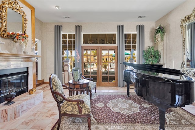 sitting room with a wealth of natural light, a tiled fireplace, and french doors